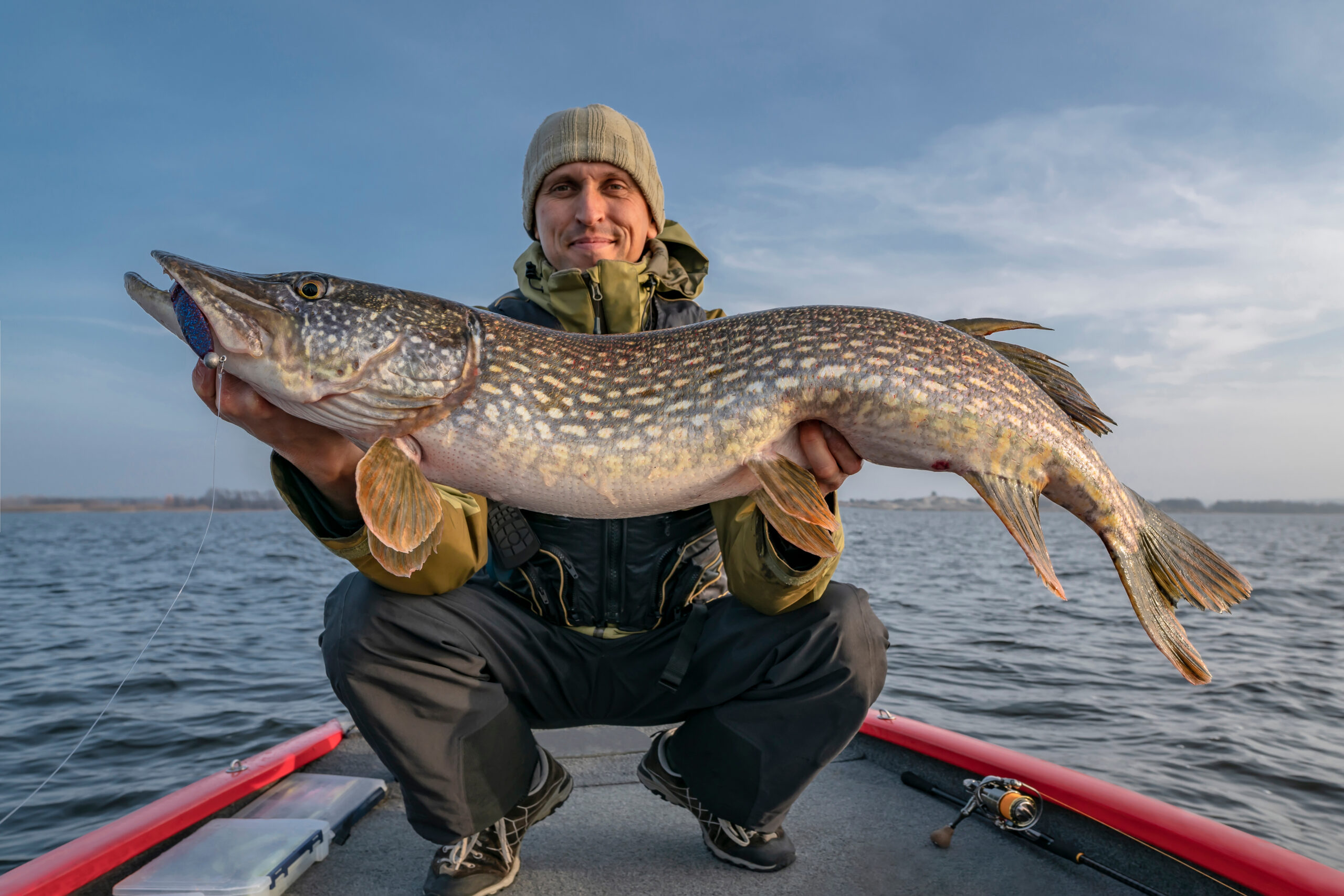 Happy fisherman with big pike fish. Boat fishing